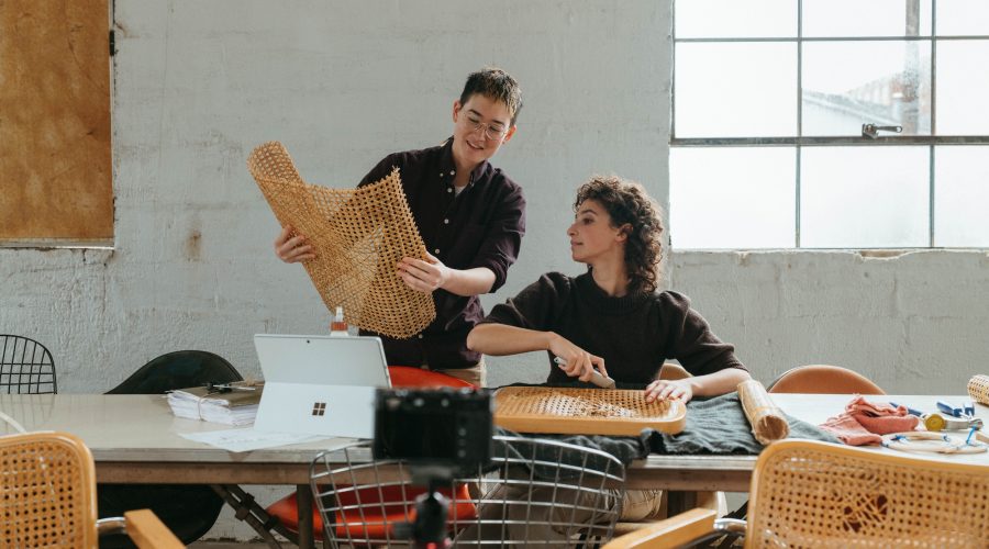 A man is standing holding a product in his hand while a women is sitting talking with him