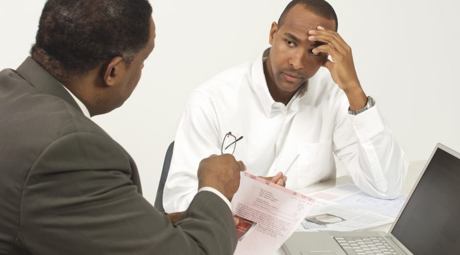 2 African-American men are sitting and talking