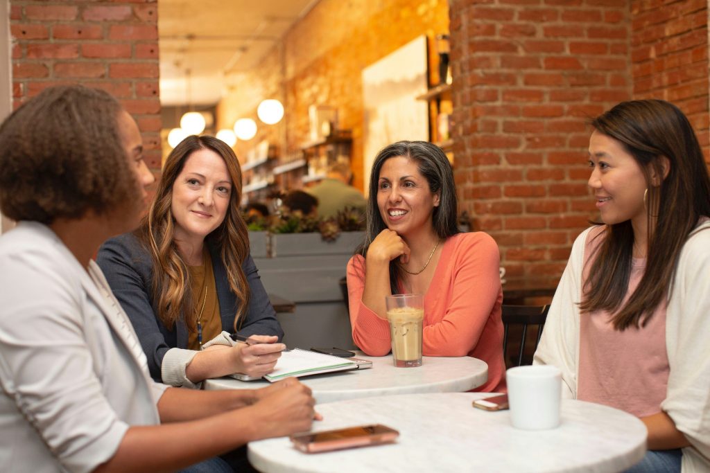 4 Ladies are sitting around a table talking