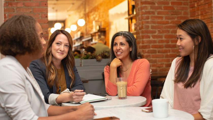 4 Ladies are sitting around a table talking