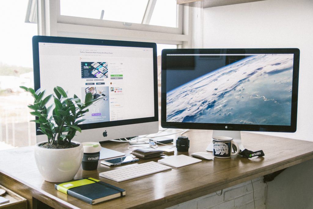 A work desk with a desktop camper, laptop computer, cell phone on it