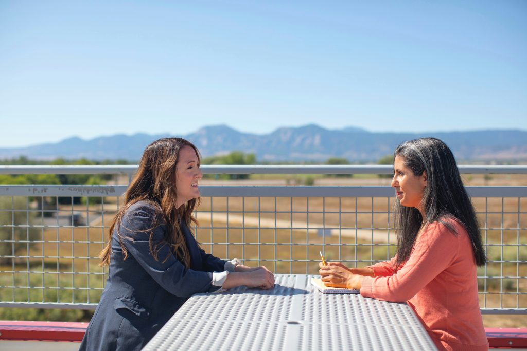 2 Woman are sitting at a table outside and talking