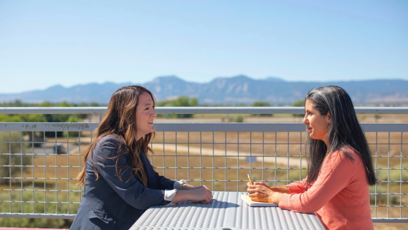 2 Woman are sitting at a table outside and talking