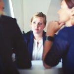 3 Women are sitting at a desk talking