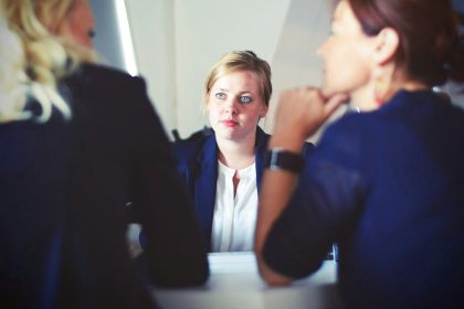 3 Women are sitting at a desk talking