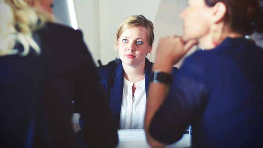 3 Women are sitting at a desk talking