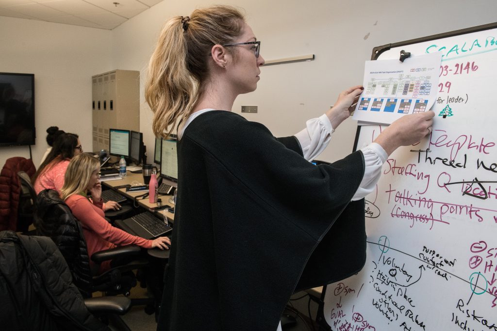 A woman is writing on white board