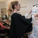 A woman is writing on white board