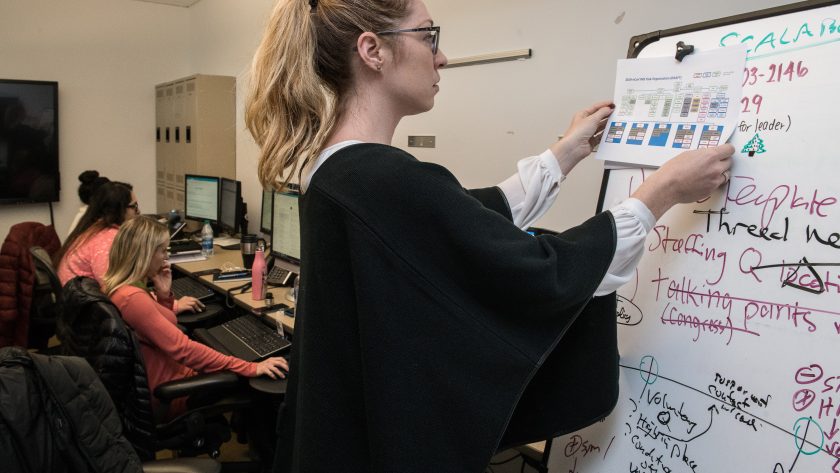 A woman is writing on white board