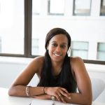 A woman is sitting at a desk smiling