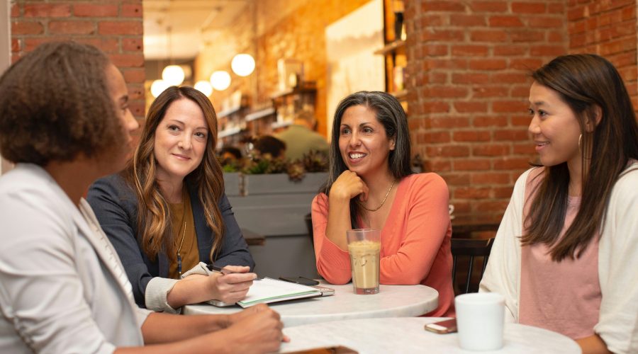 A group mod business woman are sitting at a table talking