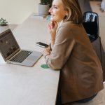 A business woman is sitting in front of a laptop computer and pondering