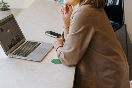 A business woman is sitting in front of a laptop computer and pondering