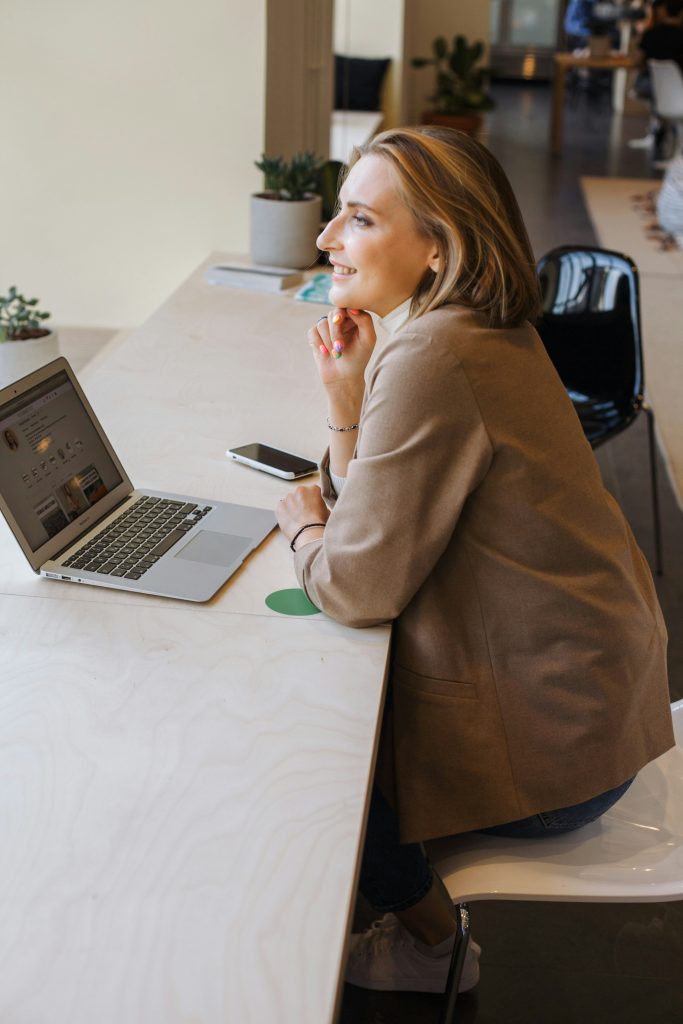 A business woman is sitting in front of a laptop computer and pondering