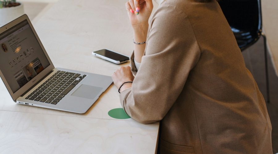 A business woman is sitting in front of a laptop computer and pondering